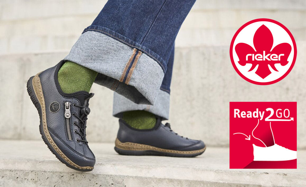 Person wearing black shoes with green socks, standing on steps, with Rieker logo in the corner.