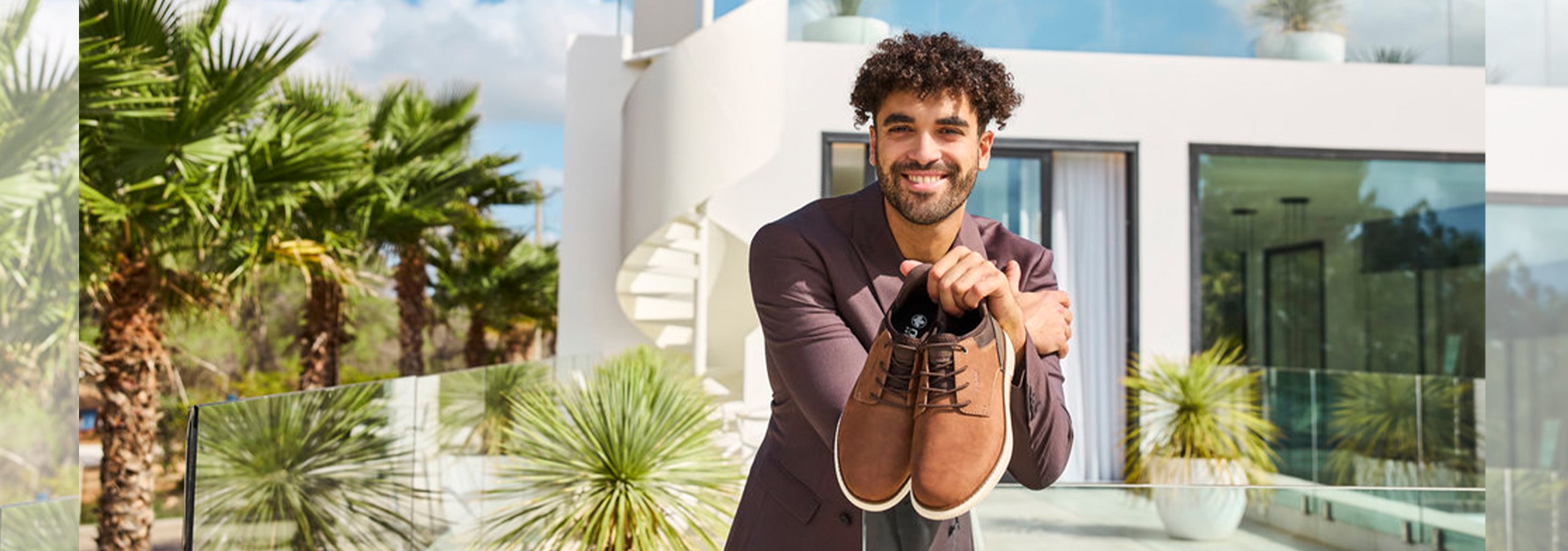 Mens Footwear - Image of man holding a pair of brown shoes