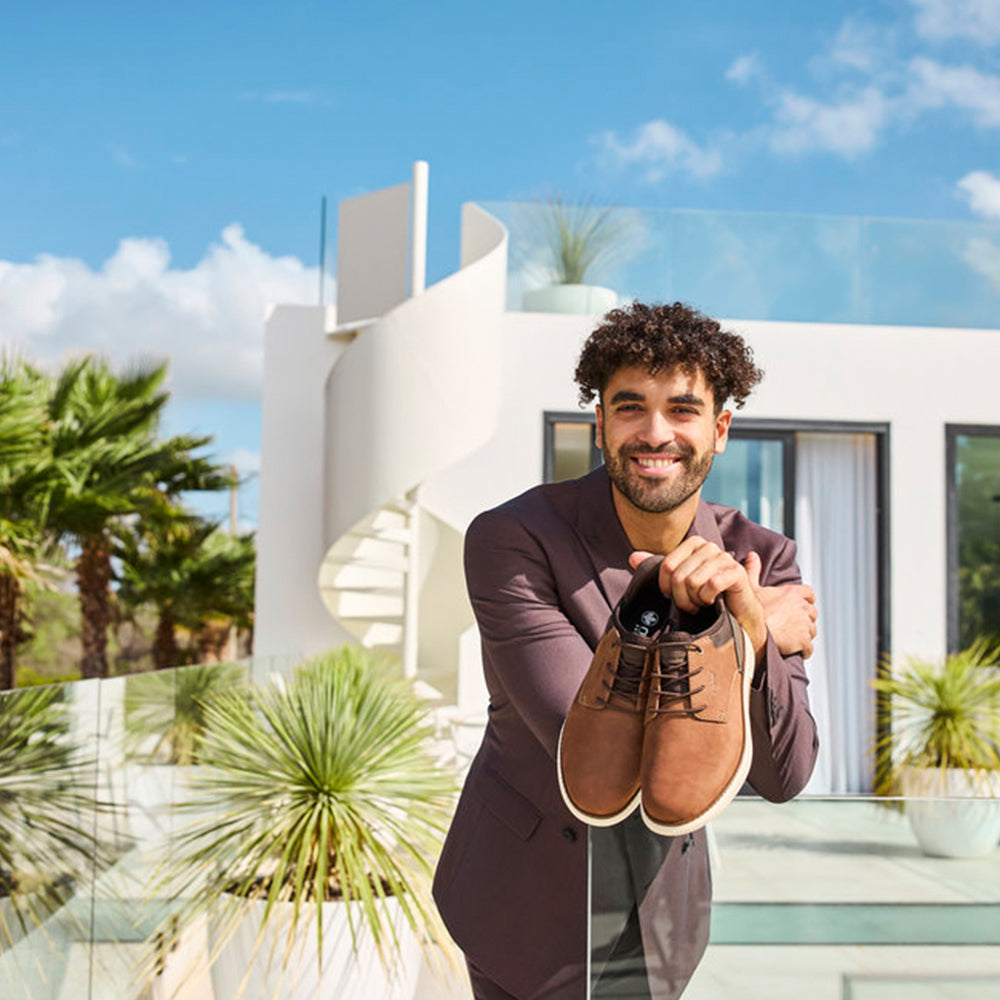 Mens Footwear - Image of man holding a pair of brown shoes